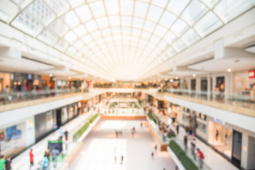 Blurred image interior of main hall shopping mall showing the ice rink and large skylight with natural light from glass roof.