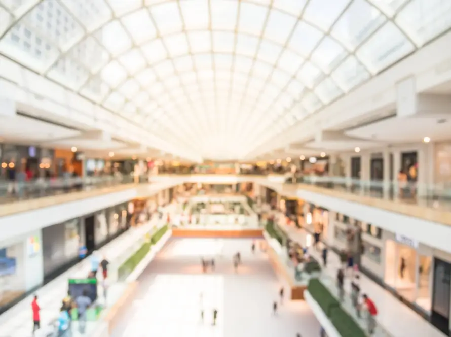 Blurred image interior of main hall shopping mall showing the ice rink and large skylight with natural light from glass roof.