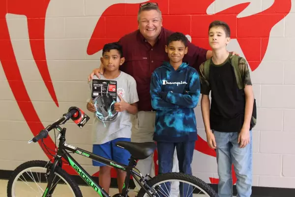 teacher with Students standing behind a bike