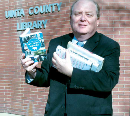 man holding book in front of the unita county library